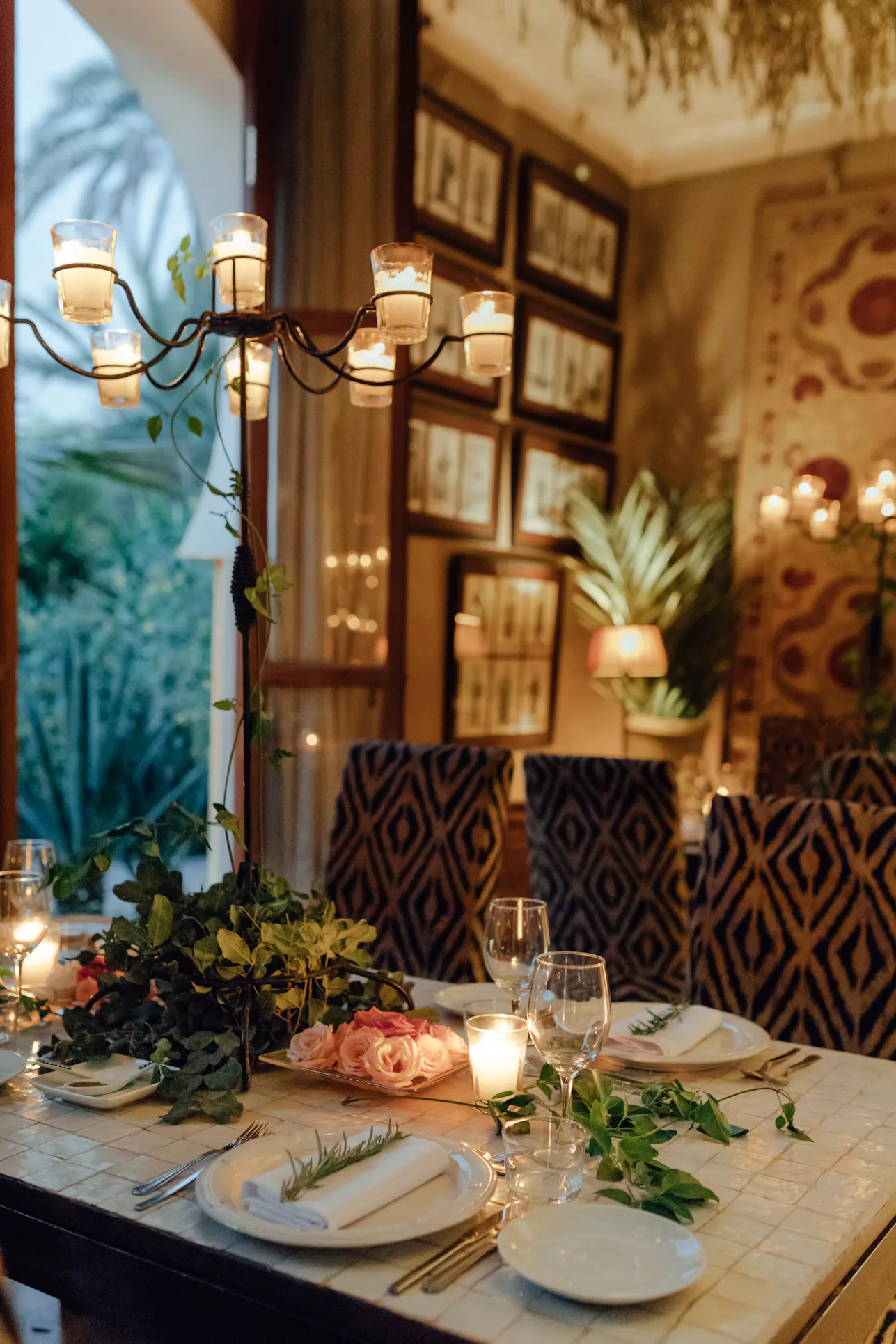 A candlelit restaurant table set with plates, glasses and greenery