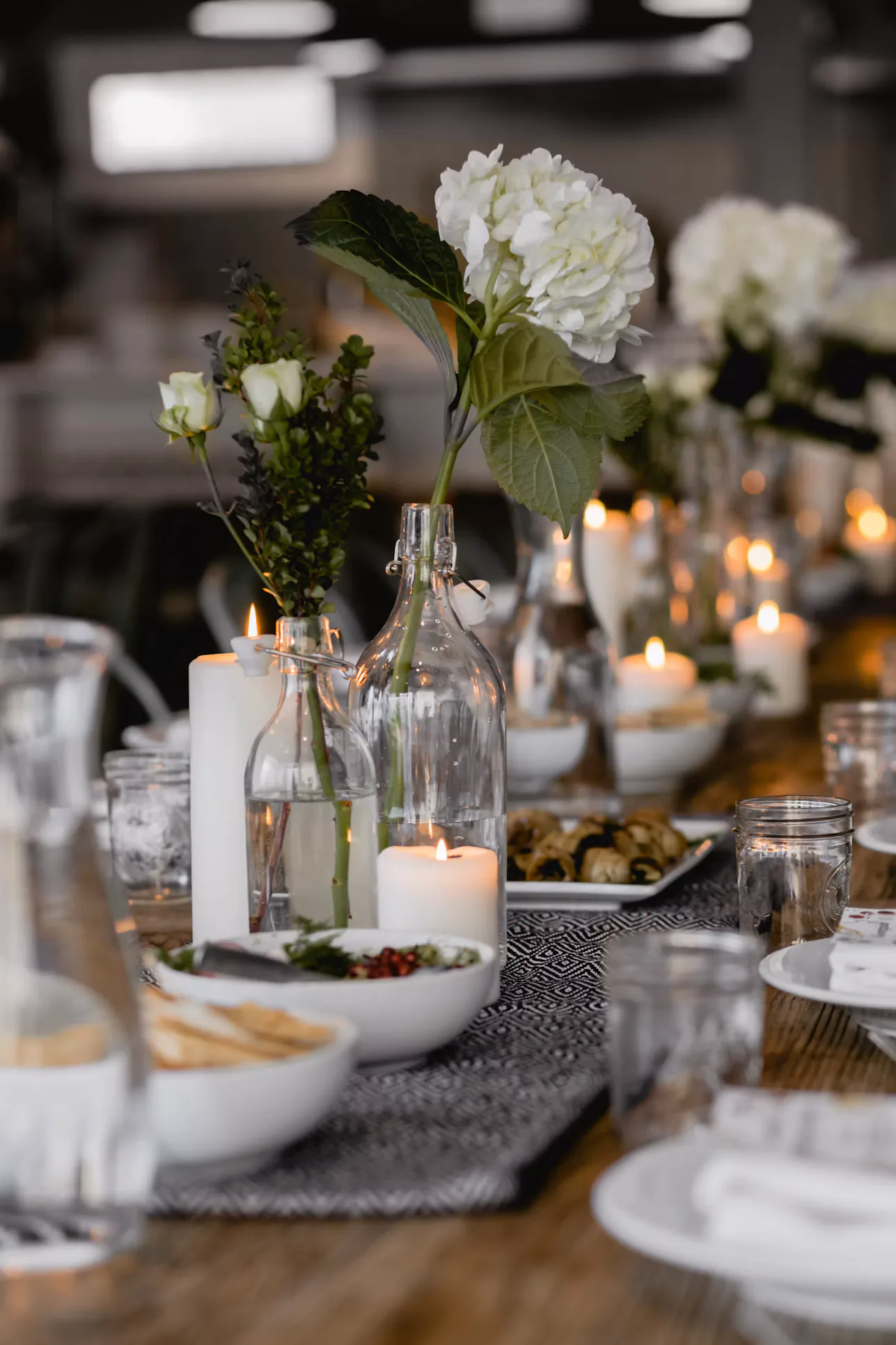 A celebration table with white flowers, candles and place settings