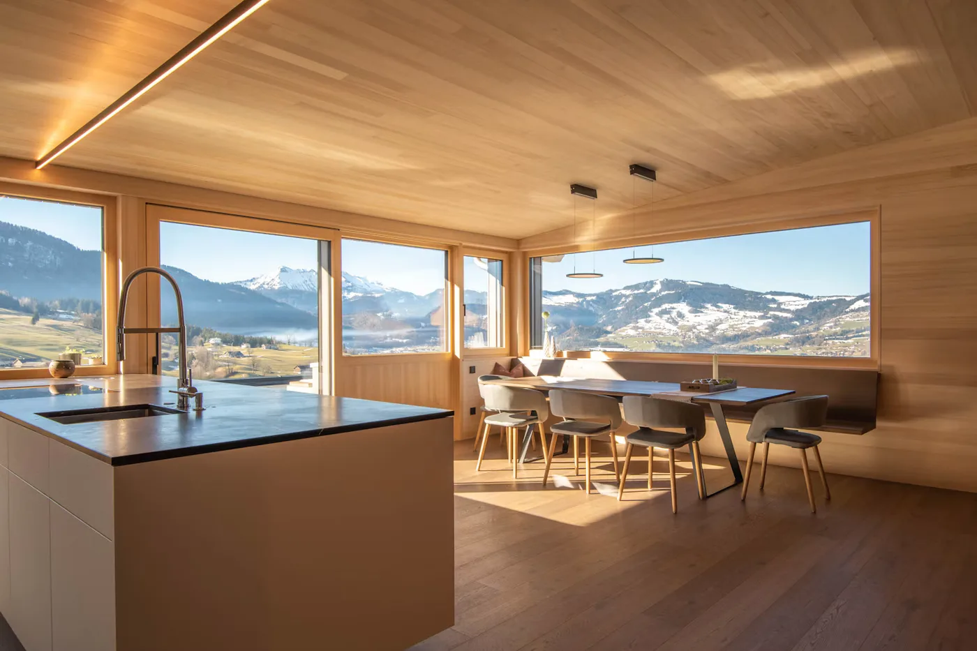 A warm timber interior with a dining area and views towards the mountains